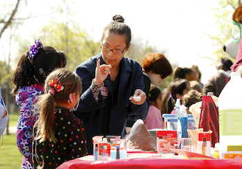 College student leading a science activity with two young children