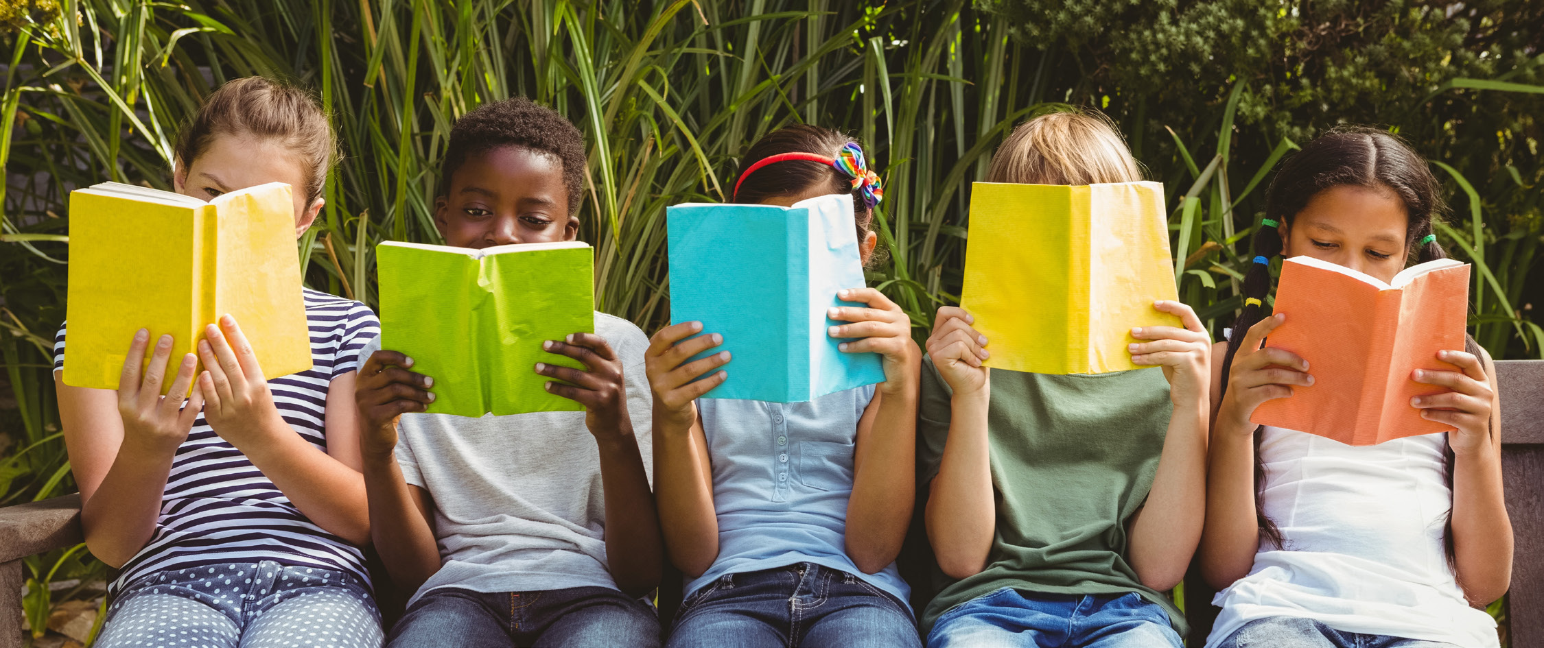 Children sitting outdoors and reading books