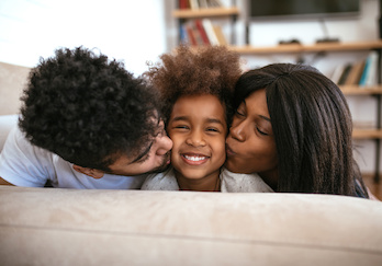 Parents kissing cheek of child