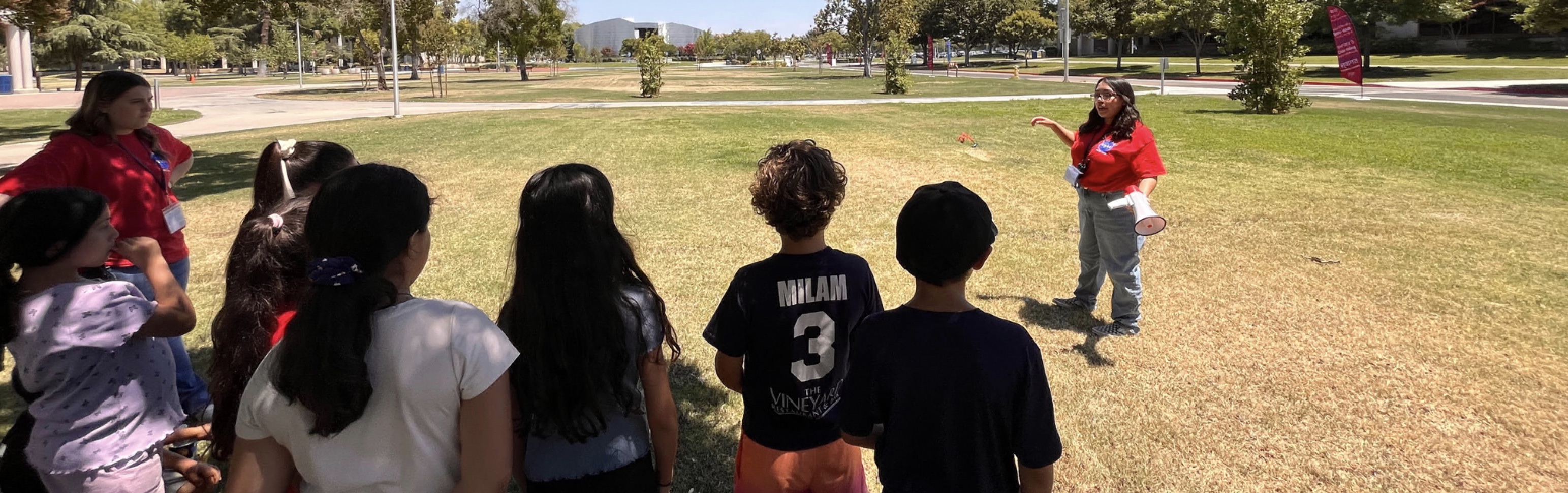 Students outside watching a tutor give instructions 