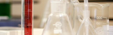 Laboratory glassware and a red graduated cylinder on a counter