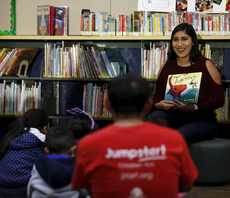 Woman reading to children sitting on floor