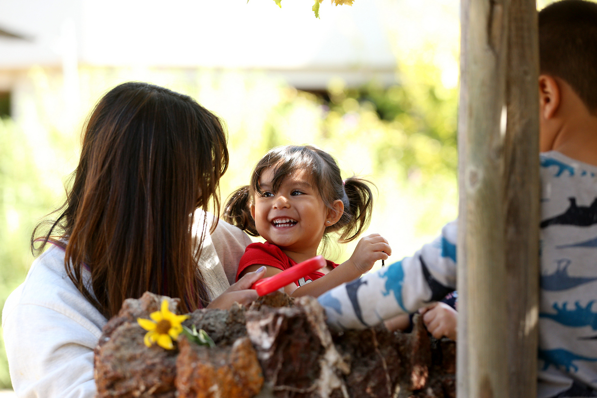 Teacher looks at a her students, a young smiling little girl.