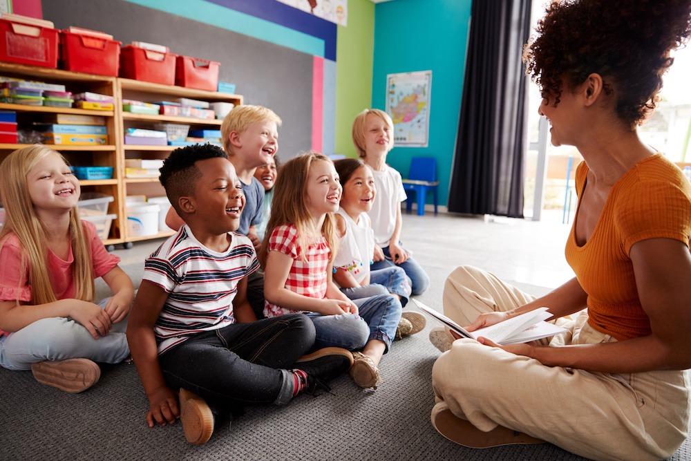 Teacher sitting on floor with students