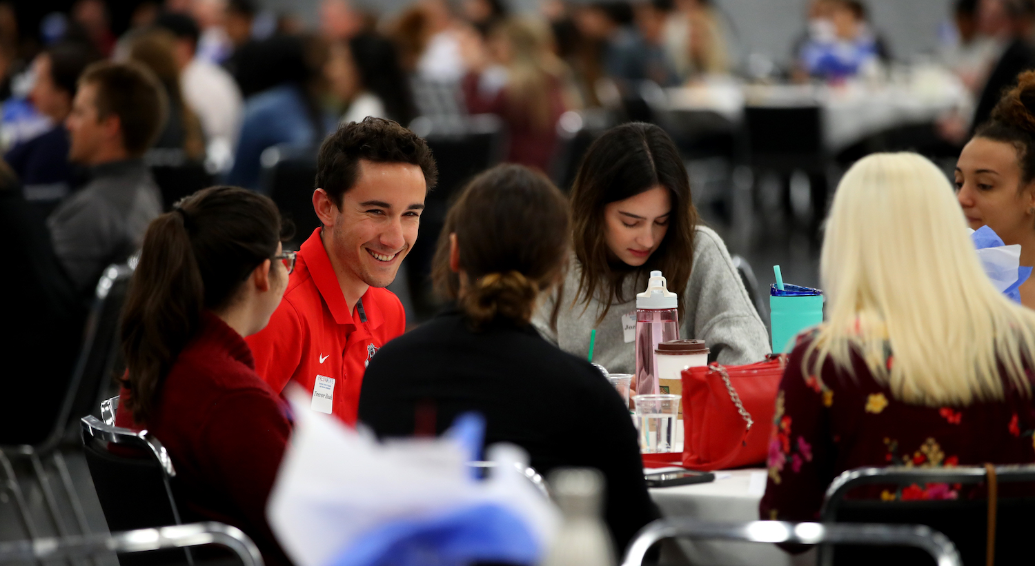 Guy smiling while sitting at table at conference.
